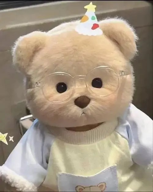 Chú gấu nâu mang chiếc áo trắng viền ren điệu đà đang ngồi ngay ngắn tạo cảm giác thân thiện và rất êm ái cho góc bàn học nhỏ xinh.